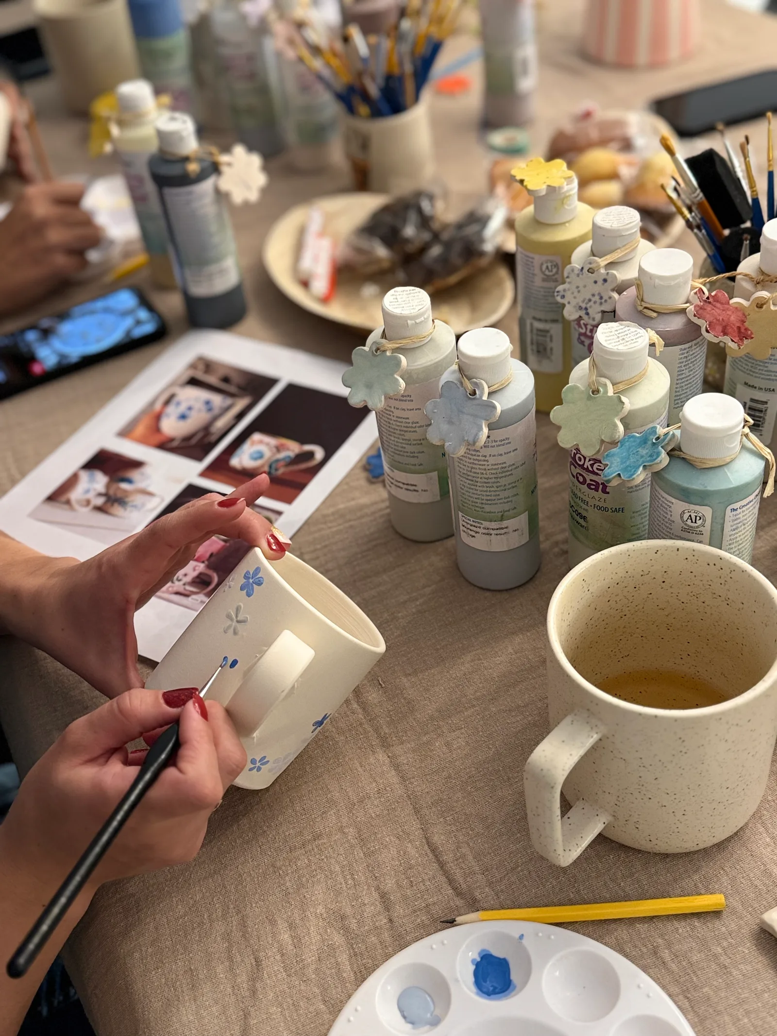 Une participante peint de petites fleurs bleues sur son mug, à l’atelier Comptoir Ceramica